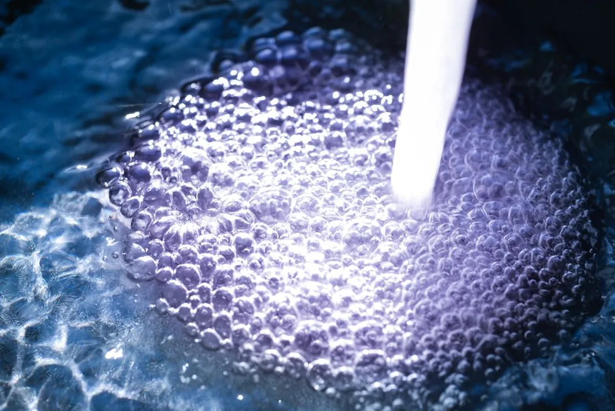 Eau en mouvement couverte de fines bulles blanches, vue de près